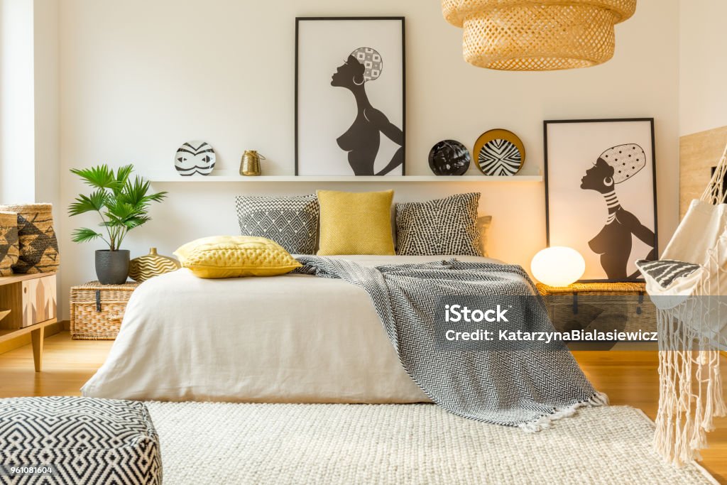 Warm modern bedroom interior Yellow and patterned pillows on bed in modern warm bedroom interior with posters and plant Bedroom Stock Photo