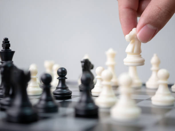 istock Strategic planning business competition concept. Hand holding white pawn moving playing chess board game. Leader and teamwork to success 961100372