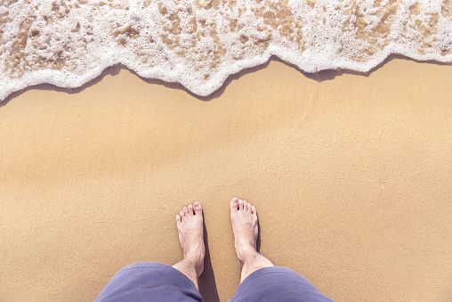 Feet on sea sand and wave with copy space, Vacation on ocean beach, Summer holiday.