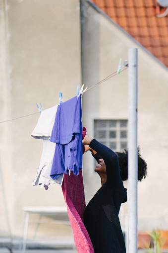 Young and beautiful woman hanging up laundry on a rooftop terrace.