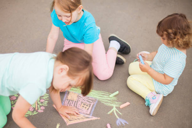 istock Little sisters draw with color chalk outdoors. Chalk drawings. 961172440