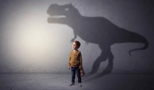 Photo of Dinosaurus shadow behind cute boy