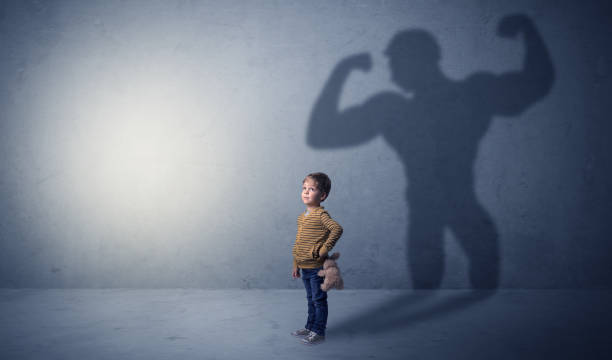 istock Muscleman shadow behind waggish little boy 961177266