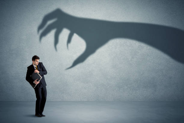 Business person afraid of a big monster claw shadow concept Business person afraid of a big monster claw shadow concept on background evil stock pictures, royalty-free photos & images