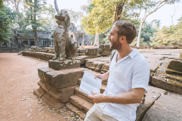 istock Young man reading guidebook at ancient temple in Cambodia 961209464
