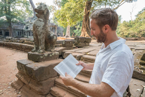 istock Young man reading guidebook at ancient temple in Cambodia 961209586