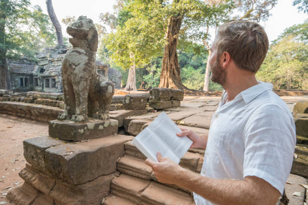 istock Young man reading guidebook at ancient temple in Cambodia 961209632