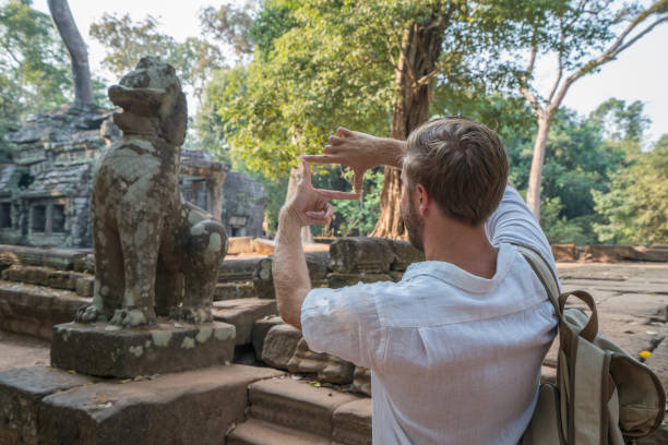 istock Young man framing ancient temple with fingers while visiting in Cambodia 961209650