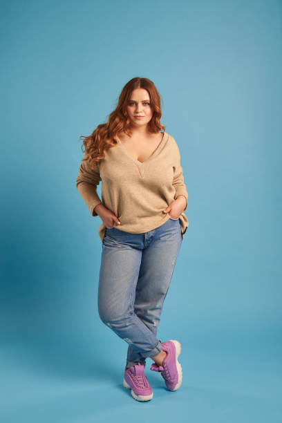 istock Confident plump girl in jeans and sweatshirt posing at studio 961209838