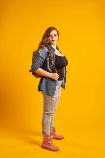 istock Confident curvy girl in denim jacket with backpack looking at ca 961210372