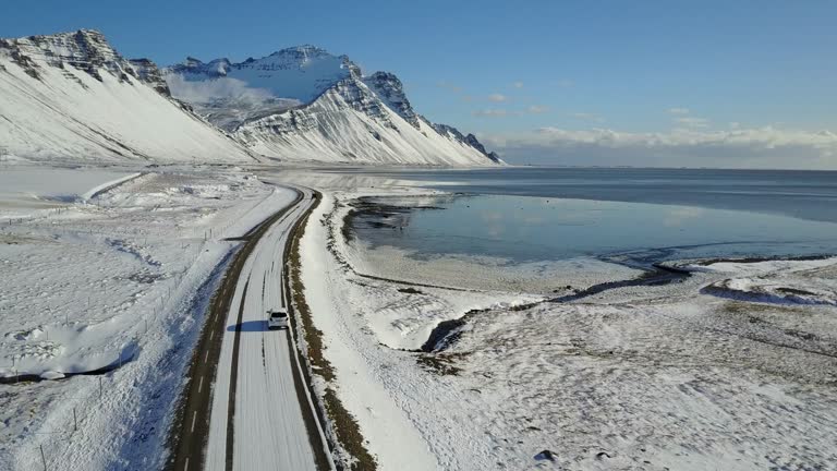 Flying over icy road with snowy mountain landscape in winter of East Coast Iceland