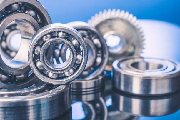 Group of various ball bearings and gears close up on nice blue background with reflections.