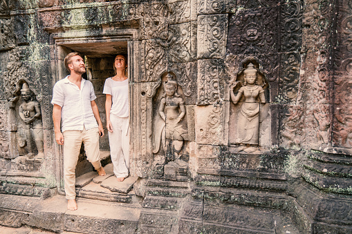 Young couple traveling in Cambodia visiting the temples of Angkor wat complex. People travel discovery Asia concept. Adventure and exploration concept in Siem Reap, Southeast Asia.