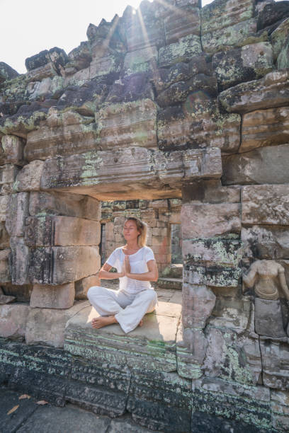 istock Young woman exercising yoga in ancient temple, sitting on old ruin's window sunlight passing through and relaxing with some meditation; concept of people with healthy lifestyles and wellbeing and travel 961237652