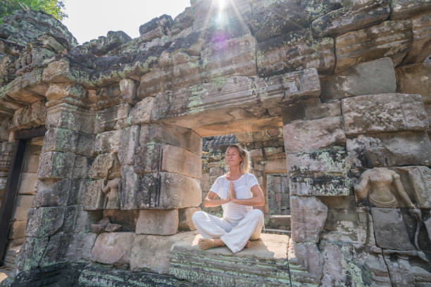 istock Young woman exercising yoga in ancient temple, sitting on old ruin's window sunlight passing through and relaxing with some meditation; concept of people with healthy lifestyles and wellbeing and travel 961237774