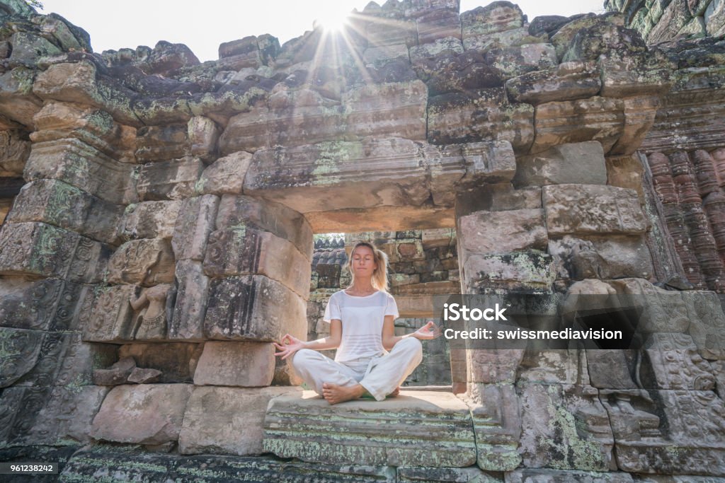 Young woman exercising yoga in ancient temple, sitting on old ruin's window sunlight passing through and relaxing with some meditation; concept of people with healthy lifestyles and wellbeing and travel Young woman exercising yoga in ancient temple, sitting on old ruin's window sunlight passing through and relaxing with some meditation; concept of people with healthy lifestyles and wellbeing and travel 
Shot at Angkor Wat, Cambodia Cambodia Stock Photo