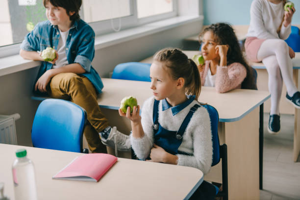istock adorable schoolchildren eating apples at classroom while having break 961238424