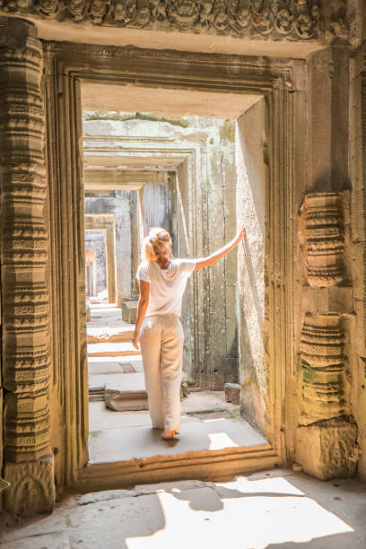 Young woman traveling in Cambodia visiting the temples of Angkor wat complex. People travel discovery Asia concept. Shot at sunset, one woman only, adventure and exploration in Siem Reap, Southeast Asia.