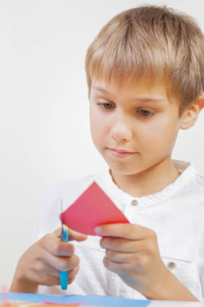 istock Child cutting red paper heart with scissors 961244322