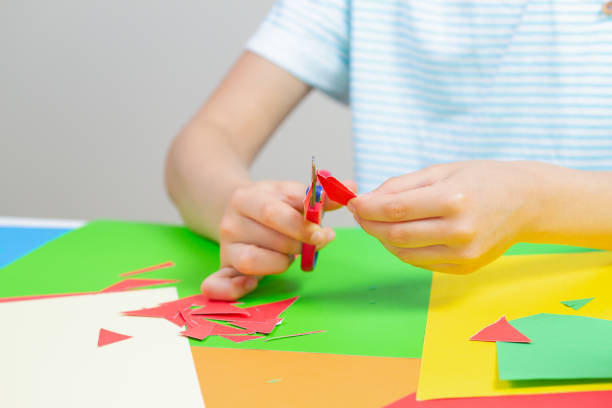 istock Child hands cutting colored paper with scissors at the table 961244684