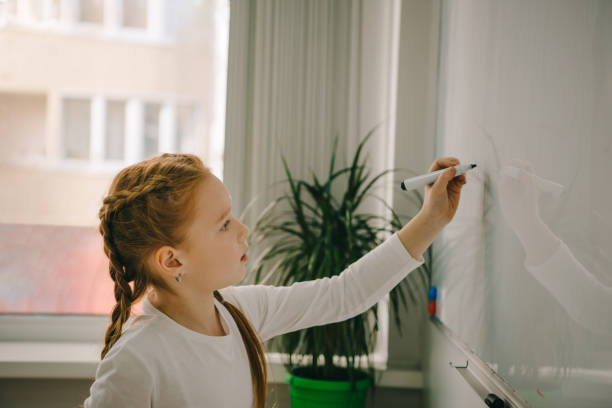 istock happy little schoolgirl writing on whiteboard 961247416
