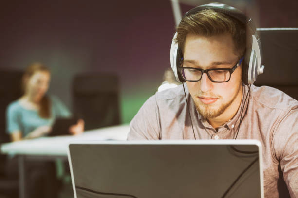 istock Young man working on laptop with headphones 961250938
