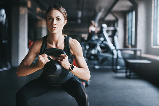 Cropped shot of an attractive young woman working out with a kettle bell in the gym