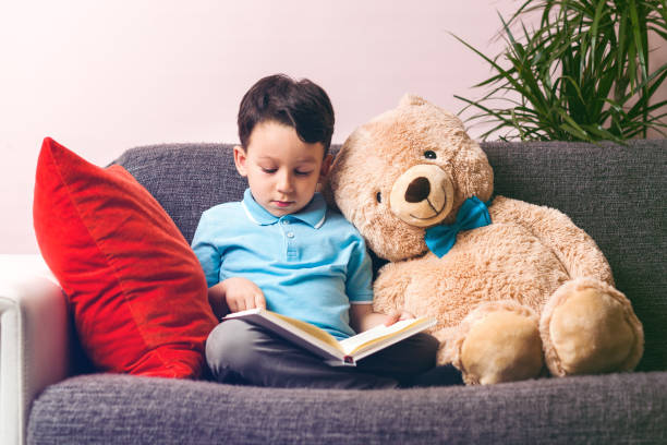 istock Little boy is reading a book to his friend teddy bear. 961260506