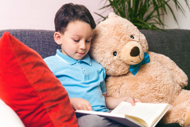 istock Little boy is reading a book to his friend teddy bear. 961262016