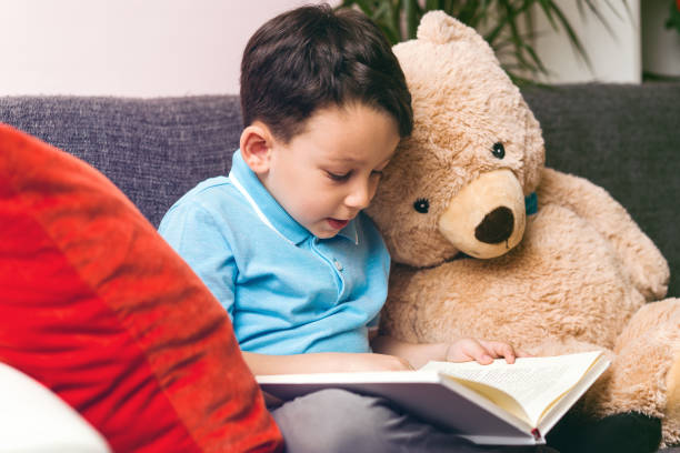 istock Little boy is reading a book to his friend teddy bear. 961262336