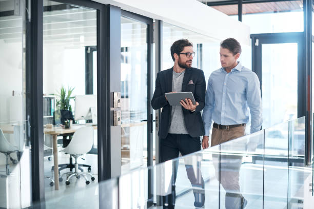 Here's what I've been working on... Shot of two businessmen using a digital tablet together in an office business stock pictures, royalty-free photos & images