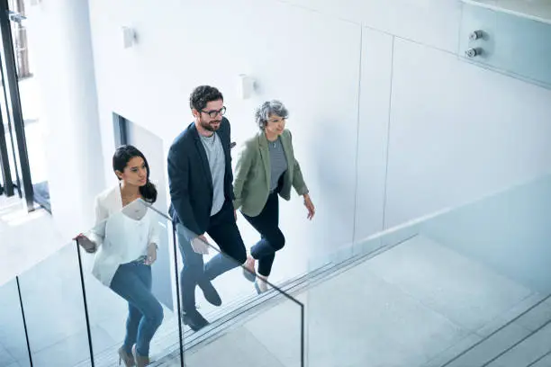 Shot of a group of businesspeople walking up a staircase in an office