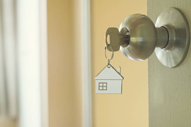 Home key with metal house keychain in keyhole, property concept stock photo