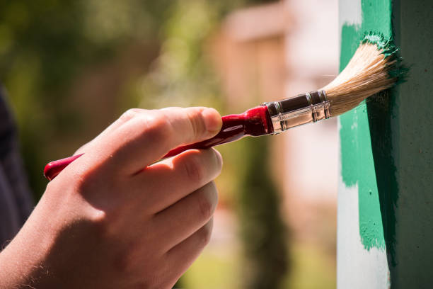 istock Man wearing gloves paint metal surface with a brush 961270690
