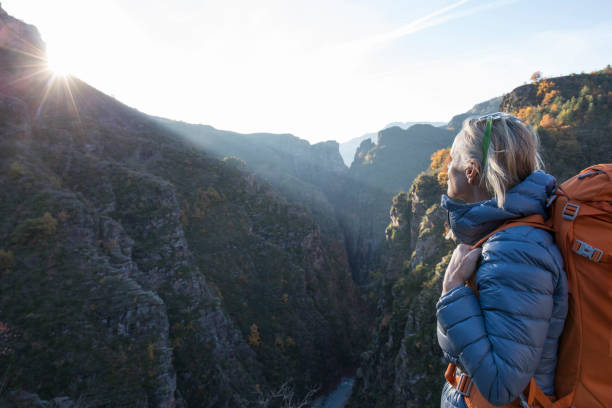 Female hiker pauses above mountain canyon at sunrise