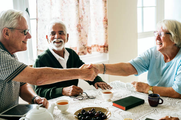 personas mayores ocasionales sacudida de las manos - senior living communitiy fotografías e imágenes de stock