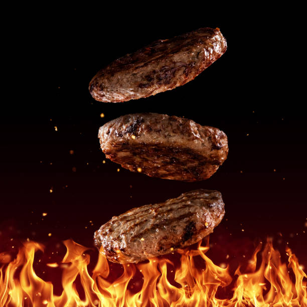 Flying beef minced hamburger pieces on black Flying beef minced hamburger pieces above grill flames, isolated on black background. Concept of flying food, very high resolution image grill burgers stock pictures, royalty-free photos & images