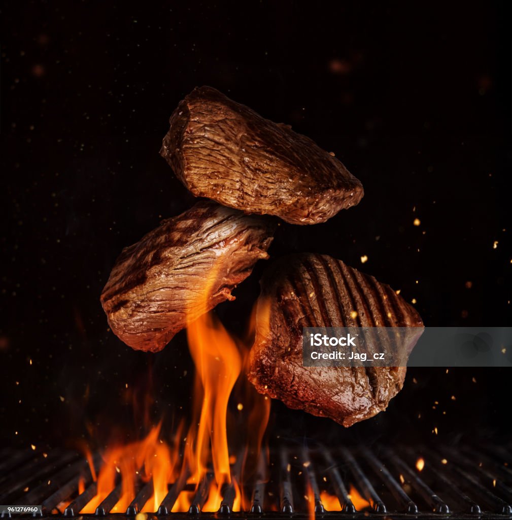 Flying pieces of beef rump steaks on black Flying pieces of beef rump steaks above grill flames, isolated on black background. Concept of flying food, very high resolution image Barbecue Grill Stock Photo