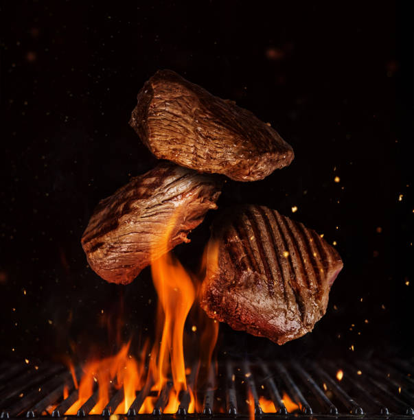 Flying pieces of beef rump steaks on black Flying pieces of beef rump steaks above grill flames, isolated on black background. Concept of flying food, very high resolution image steak vertical beef meat stock pictures, royalty-free photos & images