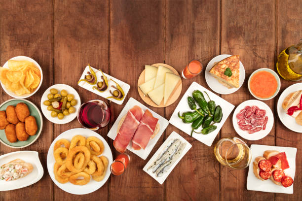 Spanish tapas food on dark background with place for text An overhead photo of an assortment of Spanish tapas food, shot from the top on a dark rustic background with a place for text. Jamon, gazpacho, cheese, wine, croquettes, calamari rings, and copy space tapas photos stock pictures, royalty-free photos & images