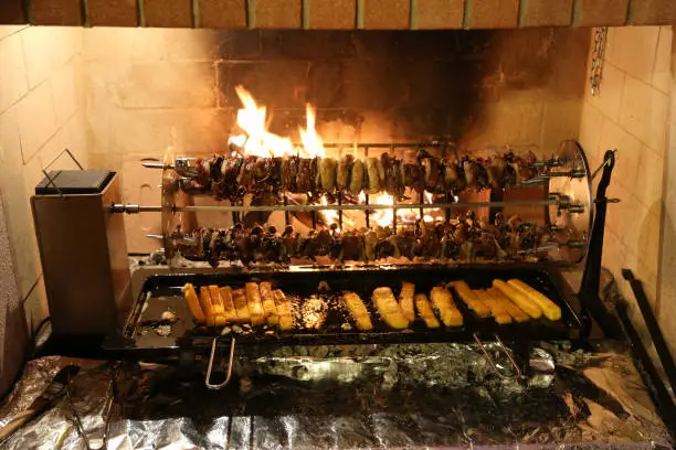 Photo of birds and polenta cooked on a spit in a fireplace