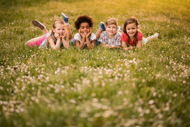 istock Four happy kids relaxing in grass during spring day in nature. 961304138