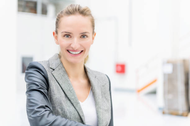 Horizontal color image of beautiful businesswoman at warehouse standing and smiling at camera.