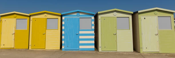istock Beach huts with green blue and yellow colours and blue sky panoramic view 961313288