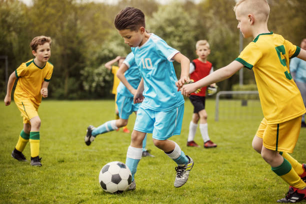 Two boys soccer teams competing for the ball during a football match Two boys soccer teams competing for the ball during a football match bouncing photos stock pictures, royalty-free photos & images