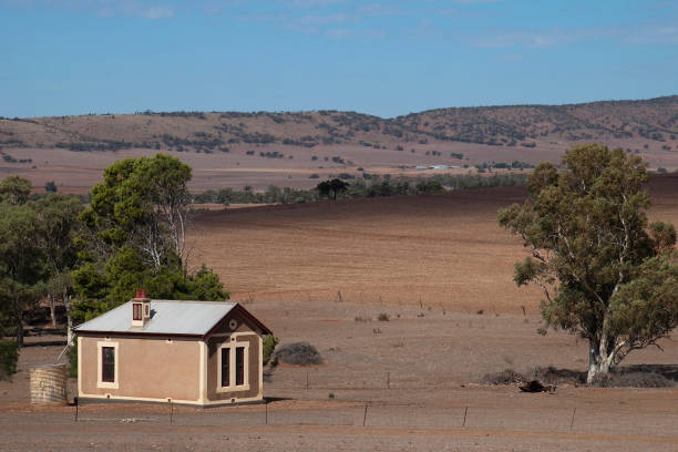 istock View across bare paddocks to rolling hills with small farmhouse in foreground 961329134