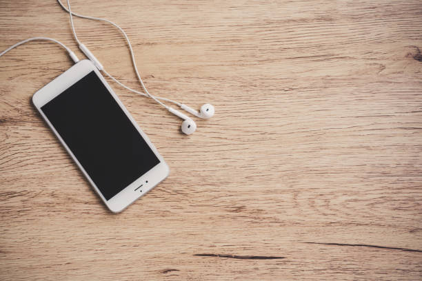 Blank screen smartphone with earphone on wooden table. top view. Copy space.