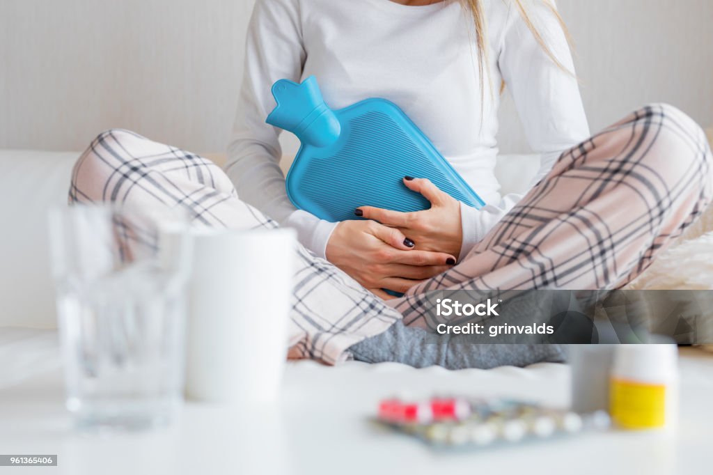 Kvinna med varmvattenflaska healing magont - Royaltyfri Menstruation - Hälsovård och medicin Bildbanksbilder