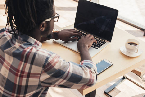 istock african american man using laptop with blank screen in cafe with cup of coffee 961369572
