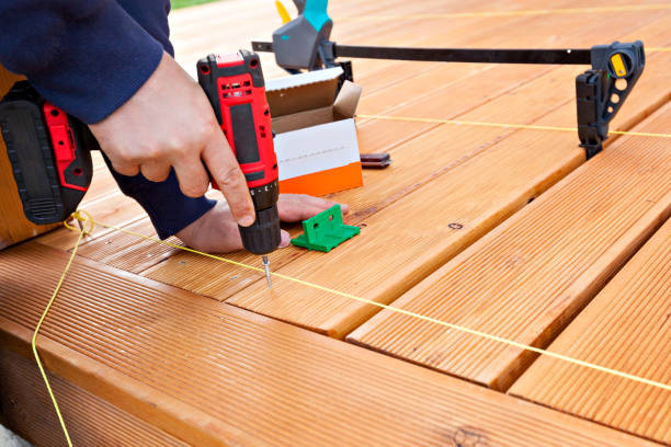 istock Construction worker screwing down wood deck with battery power screw gun or drill. 961371794